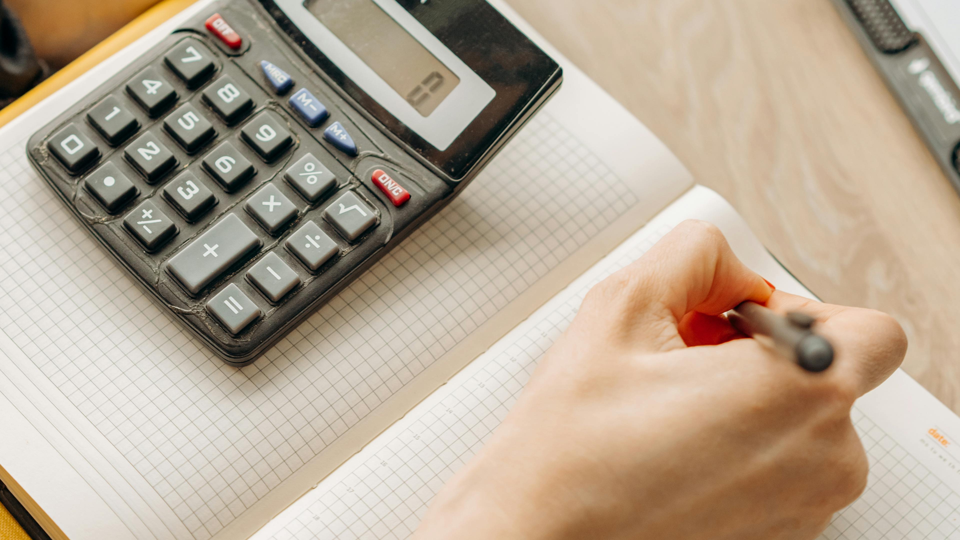 Consultant in navy blazer reviewing pricing strategy with calculator and laptop